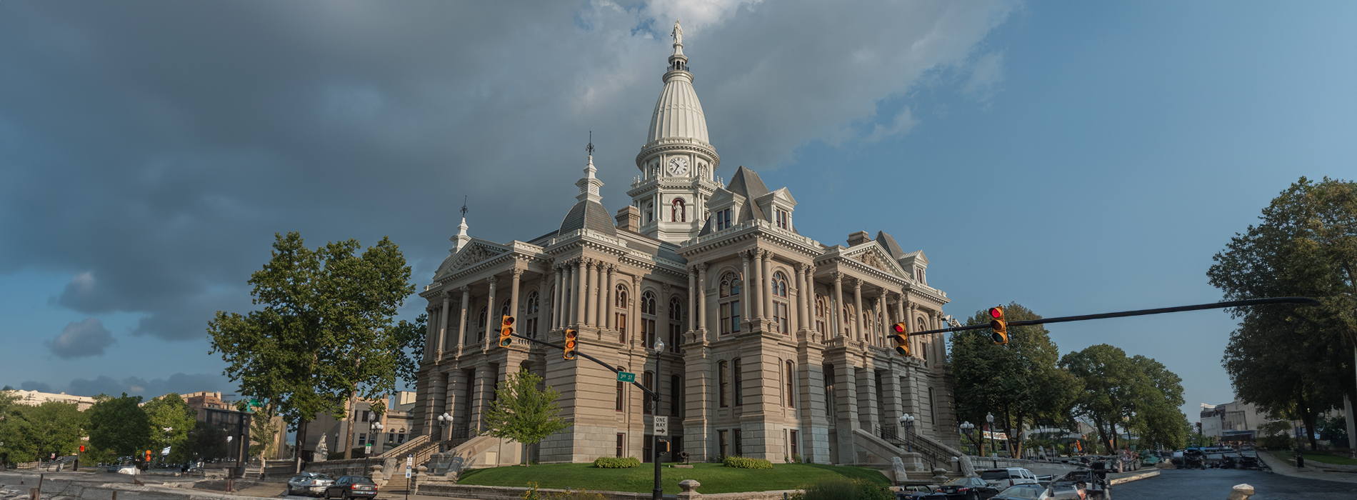 The image depicts a grand, ornate building with multiple columns and a dome, situated in an urban environment with clear skies.