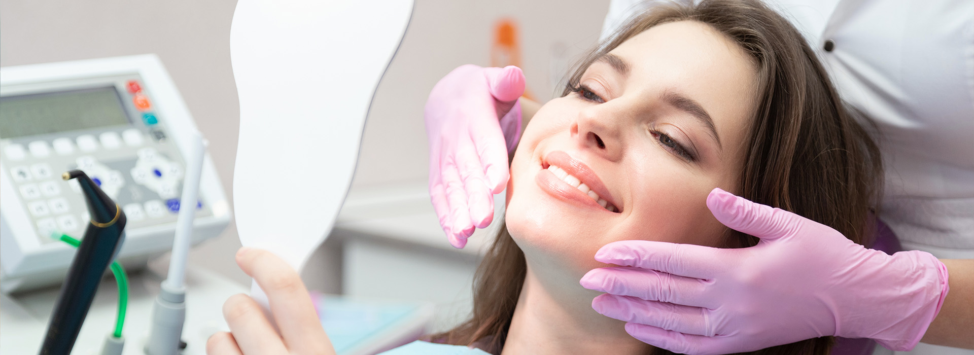 A woman receiving dental care with a dentist using a handheld device.