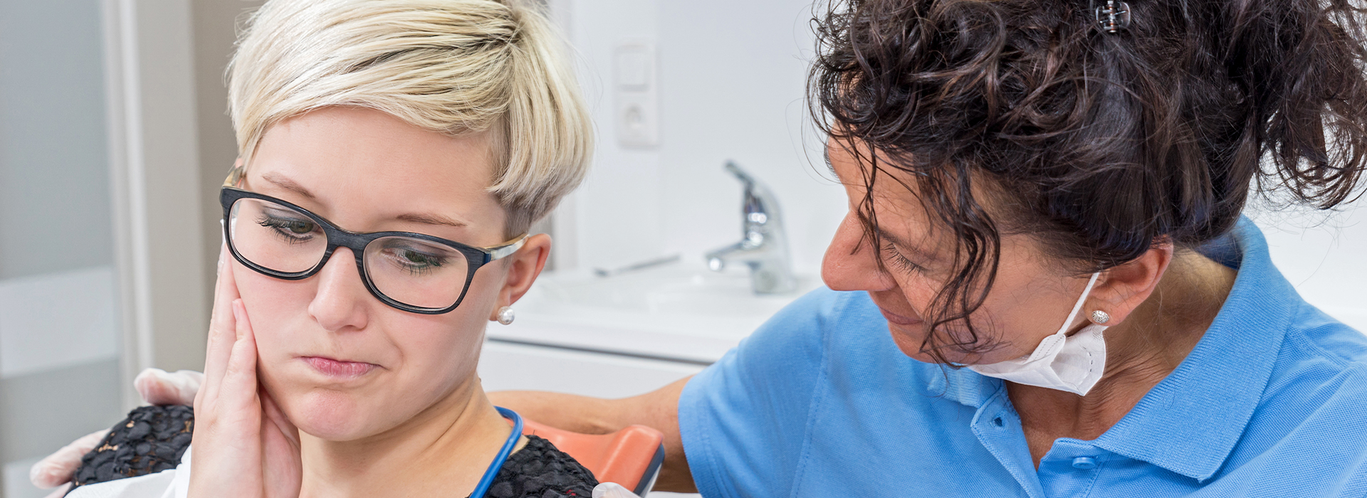 A dental hygiene professional performing a teeth cleaning procedure on a patient.