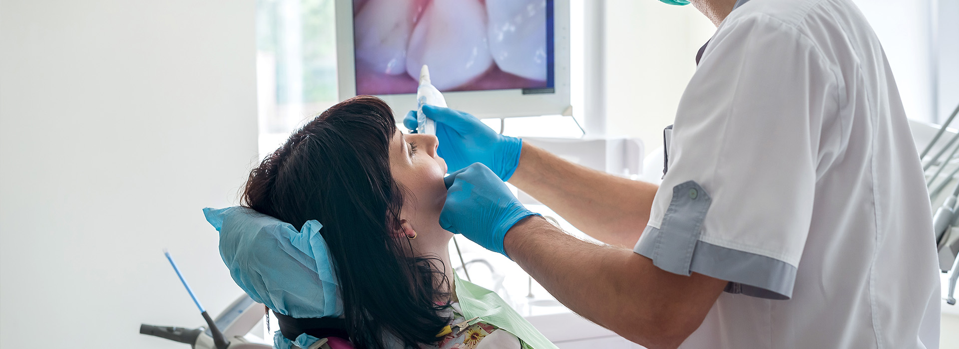 A dental professional performing a procedure on a patient, captured from an overhead angle.