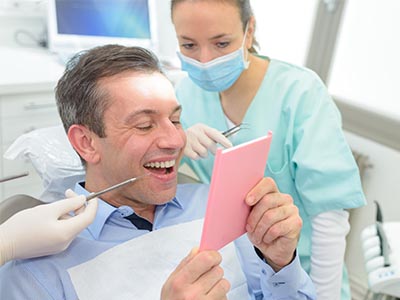 Man holding up a pink card in front of his face, surrounded by dental equipment and personnel.