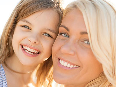 A woman and a young girl smiling at the camera, with the woman s face partially obscured by a digital overlay.