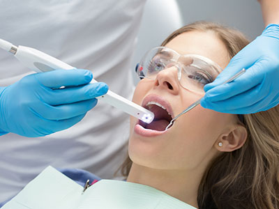 The image depicts a dental professional using a dental device to clean a patient s teeth.