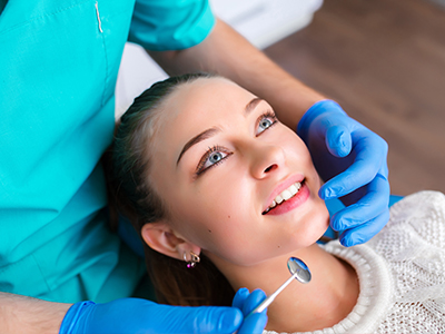 A dental professional performing a teeth cleaning procedure on a patient in a clinical setting.