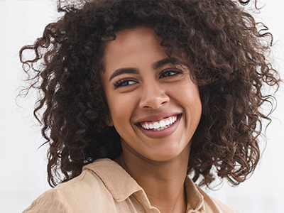 The image shows a person with curly hair, smiling at the camera.